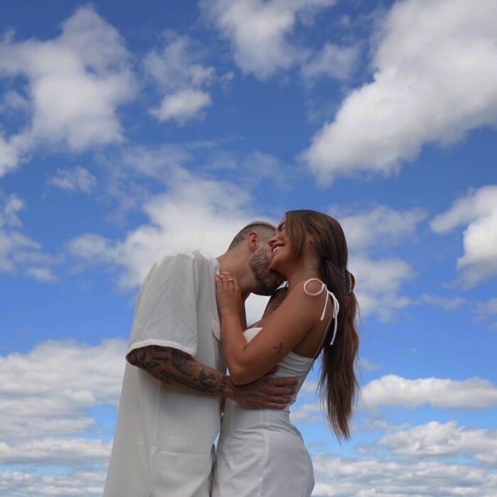 Pareja con ropa blanca besándose con el cielo de fondo