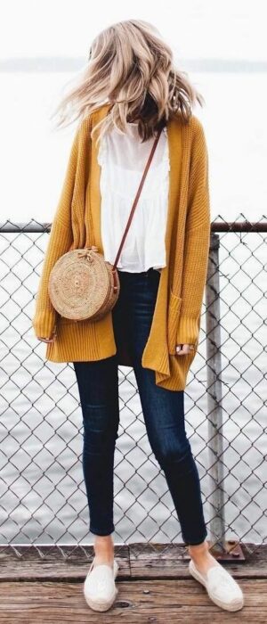 Chica usando cardigan largo color mostaza, con blusa blanca, leggings y tenis blancos