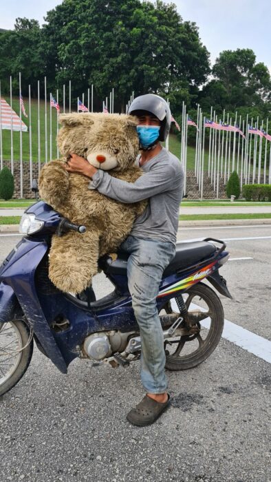 Hombre en motocicleta cargando un oso de peluche