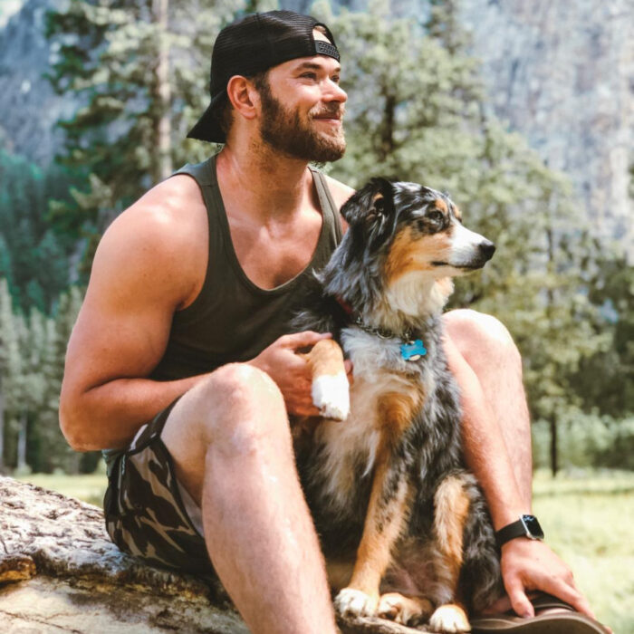 Famosos que han adoptado mascotas, perros o gatos; Kellan Lutz en la naturaleza con su perro pastor australiano ovejero color café, negro y blanco, Koda