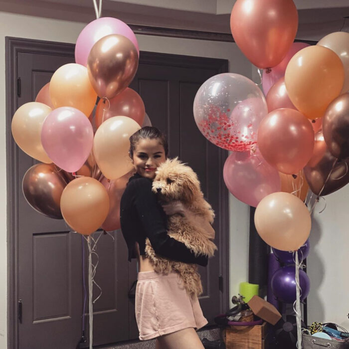 Famosos que han adoptado mascotas, perros o gatos; Selena Gomez en fiesta de cumpleaños con globos y su perrito french poodle café, Winnie