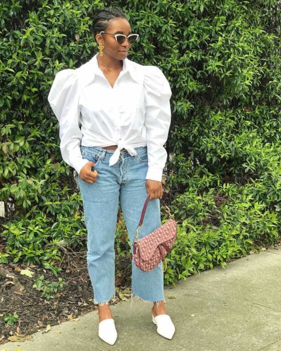 Chica usando una camisa de botones color blanca con jeans y flats 