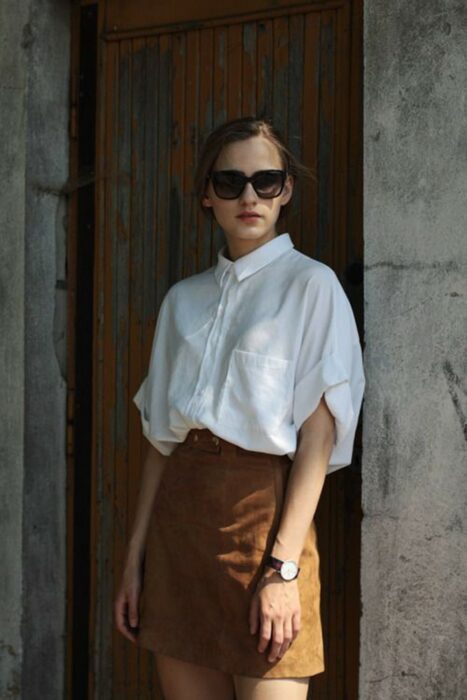 Chica usando una camisa blanca junto con una falda de color café