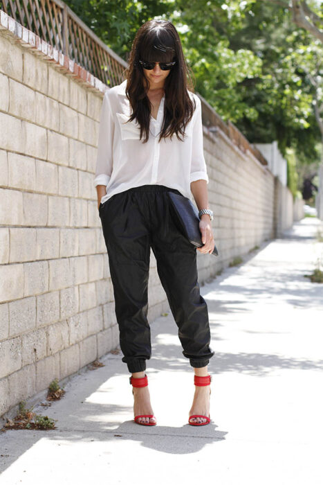 Chica usando una camisa blanca de botones fajada con un pantalón de color negro y zapatos de color rojo 