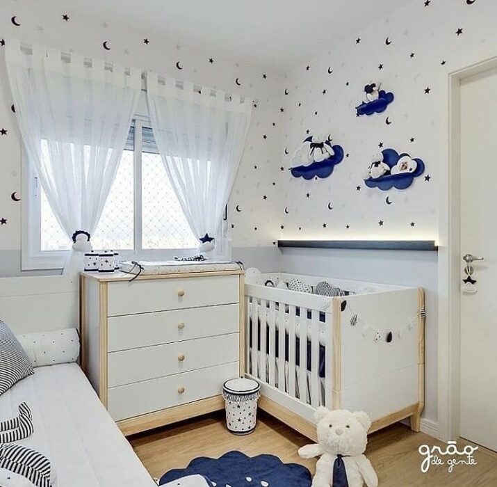 Decoración del cuarto del bebé en tonos azules con blanco con una cama y una cuna separadas por un cambiador en medio de ambas 