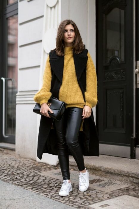 Chica llevando chaleo oversize de gamuza con suéter amarillo; ideas para llevar chaleco durante el otoño-invierno