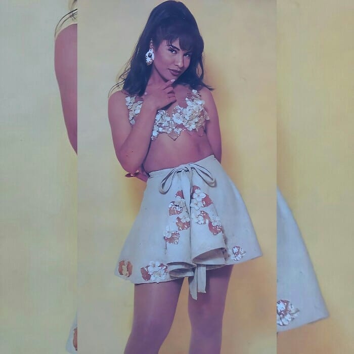 Selena Quintanilla usando un crop top en color beige con una falta a juego y detalles de flores 