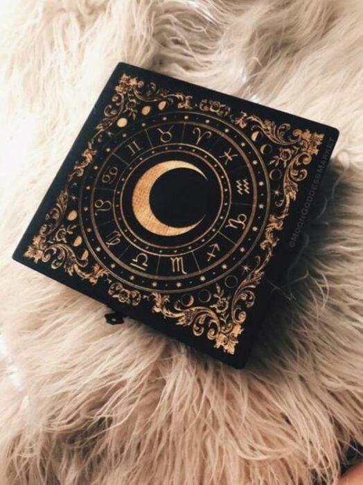 Artículo decorativo inspirado en la Luna de una caja de madera oscura con una Luna y los signos del zodiaco a su alrededor en color dorado