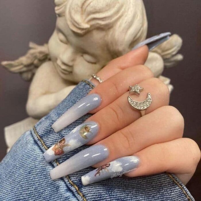 Manicura de acrílico estilo aesthetic de color azul, con diseño a mano alzada de angelitos y cielo