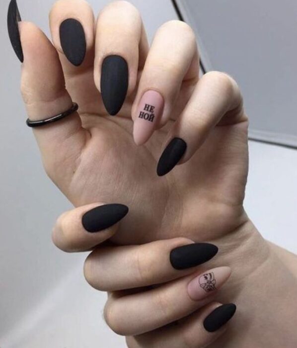 Manicura inspirada en noche de brujas de color negro con una en color nude con detalles en color negro