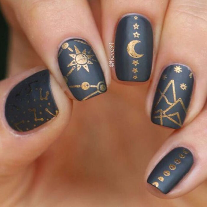 Manicura inspirada en noche de brujas de fondo color negro con detalles en color dorado