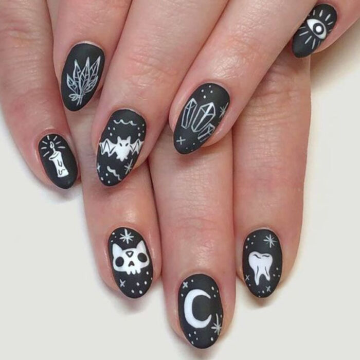 Manicura inspirada en noche de brujas de fondo color negro con detalles color blanco