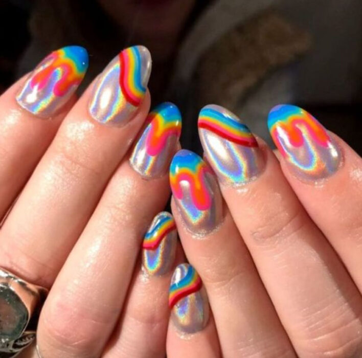 Manicura de acrílico estilo aesthetic de color plateado tornasol, con líneas azul, amarillo y rojo