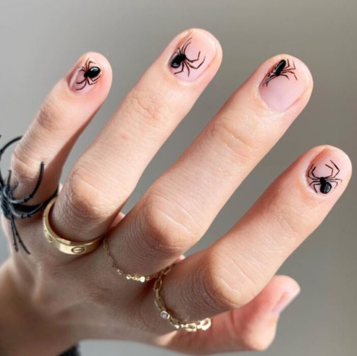 Manicura inspirada en noche de brujas de fondo transparente con detalles de arañas en color negro