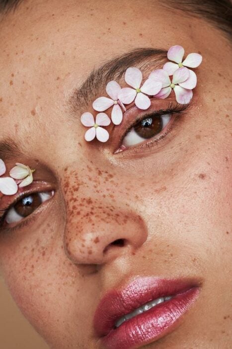 Maquillaje creativo con detalles de flores sobre sus parpados