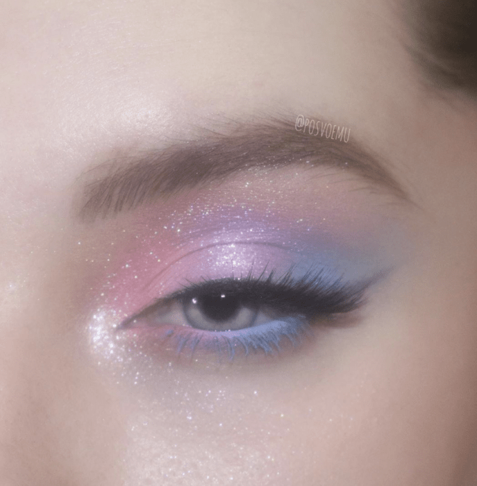 Chica con un maquillaje de ojos en glitter de color rosa, morado y azul 