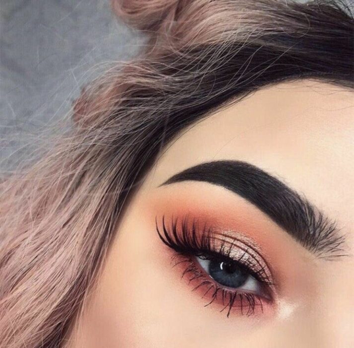 Chica con un maquillaje de ojos en colores cálidos de dorado con rosa 