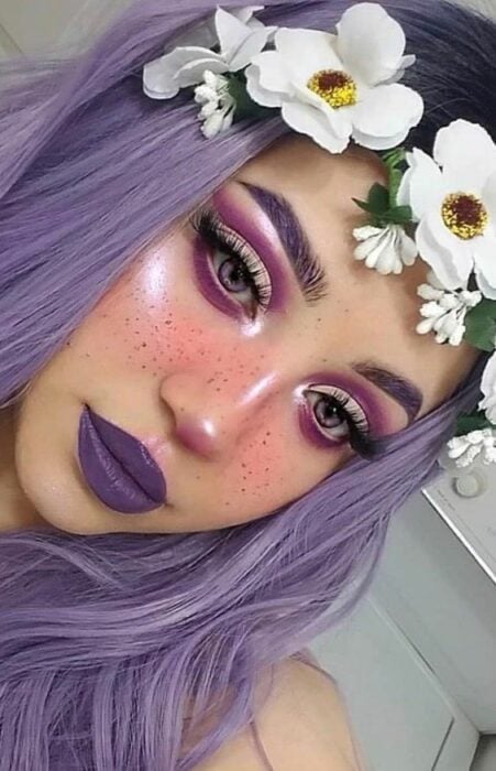 Chica con maquillaje para Halloween en colores morados con flores en la cabeza