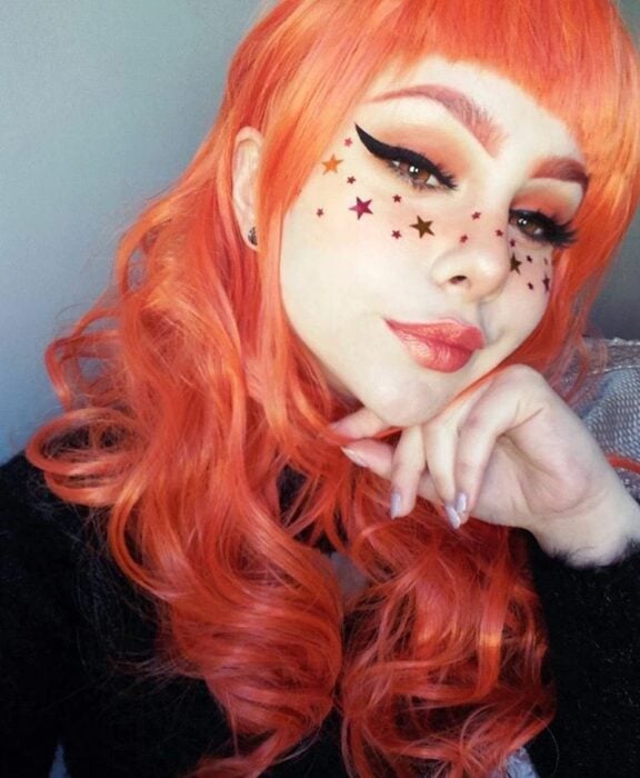 Chica usando stickers de estrellas como maquillaje