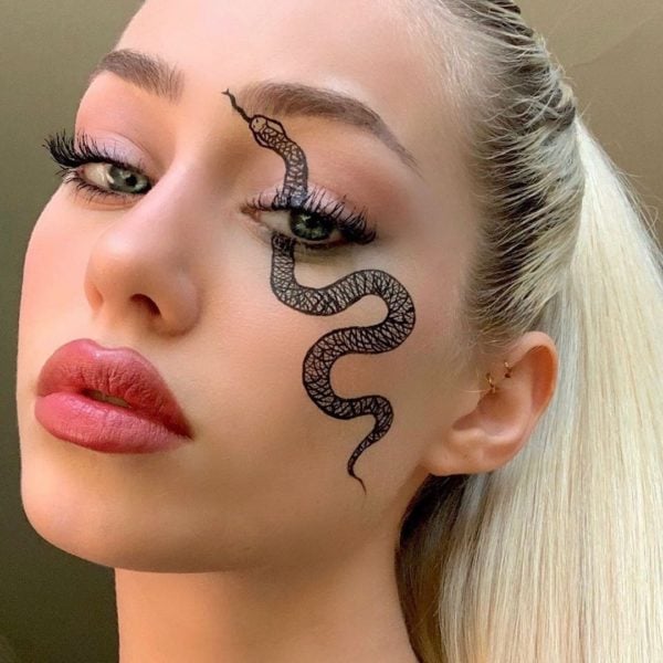 Chica con maquillaje para Halloween de una serpiente en el ojo