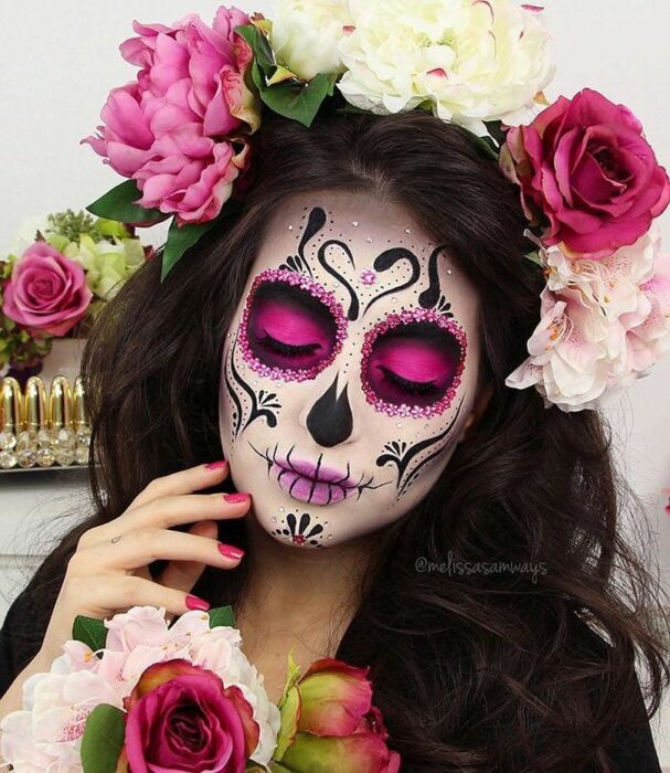 Chica con un maquillaje de catrina en colores rosas con blancos 