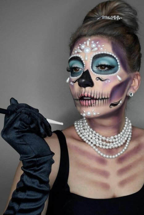 Chica con un maquillaje de catrina en colores azules con perlas 