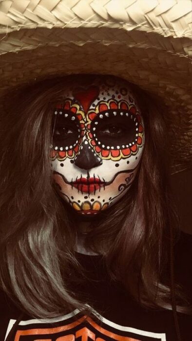 Chica con un maquillaje de catrina en colores naranja con blanco