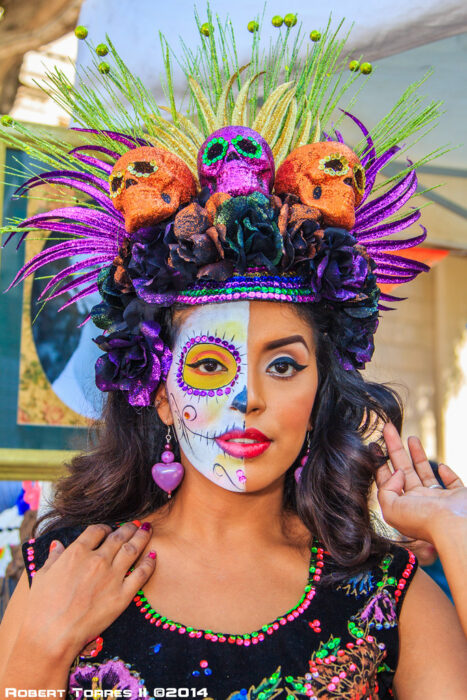 Chica con un maquillaje de catrina en colores blancos con amarillo y morada 