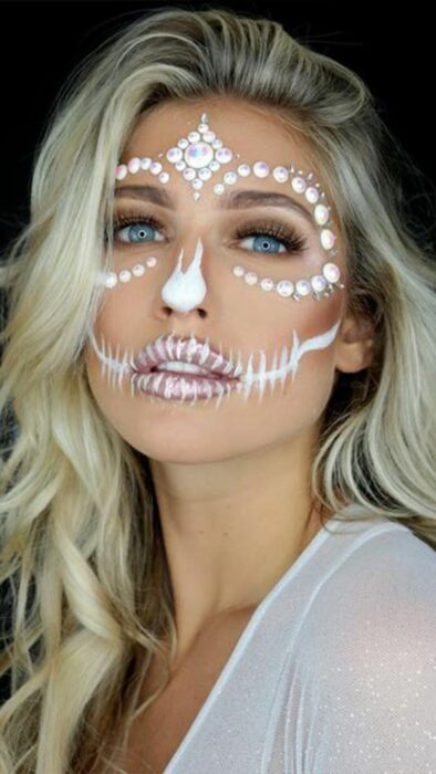 Chica con un maquillaje de catrina en colores blancos con perlas