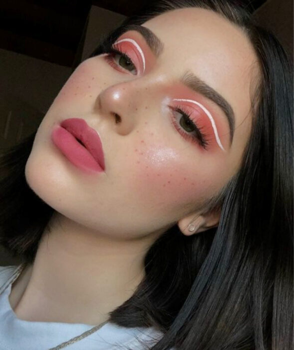 Maquillaje bonito y a la moda para oficina; sombra rosa, delineador blanco gráfico y peca