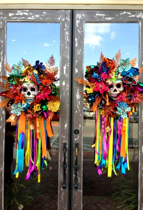 Decoración de Navidad con temática mexicana; coronas para la puerta con calaveras flores, listones de colores azul, verde, amarillo, anaranjado, rosa, azul y morado