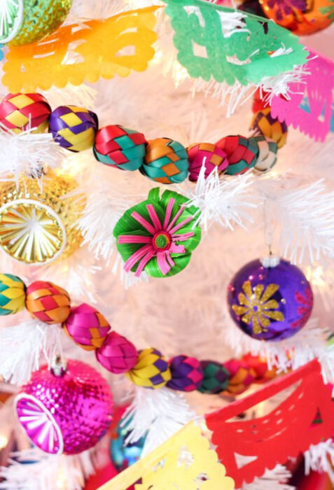 Decoración de Navidad con temática mexicana; árbol navideño blanco con adornos coloridos de México, guirnaldas y flores de hoja de palma, amarillo, rojo, morado, verde, azul, rosa, esferas, papel picado