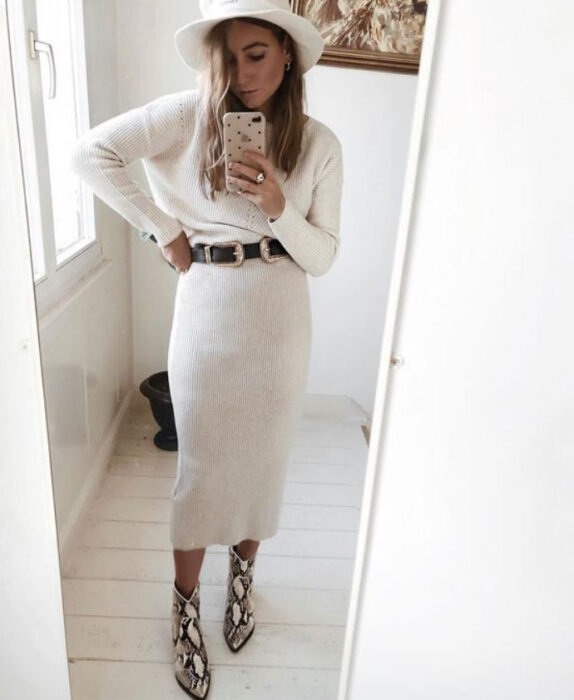 Chica usando un total white look de falda midi, botas, blusa de manga larga y sombrero