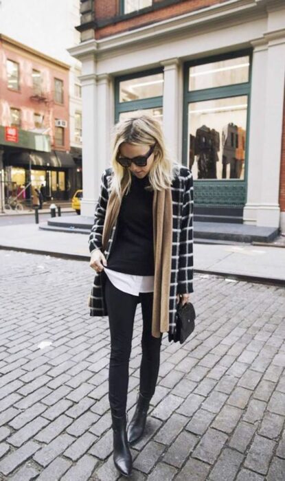 Outfit para la oficina de otoño-invierno de asco negro a cuadros, suéter negro, camisa debajo blanca y jeans y botines negros con bufanda color caki