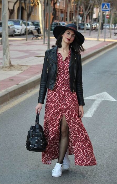 Chica usando sombrero de color negro con outfit de tenis blancos, maxi vestido rojo con lunares y chamarra de piel negra