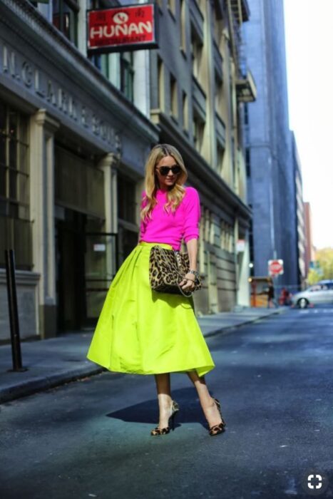 Chica usando un outfit en colores neón con falda verde y blusa de color rosa 