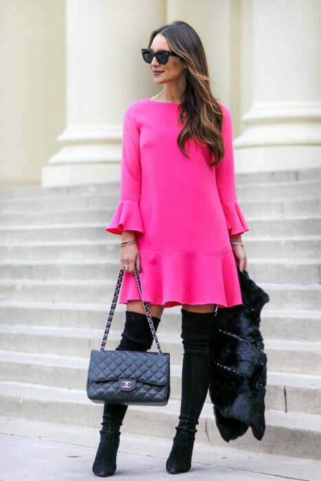 Chica usando un vestido de color rosa con botas altas y chaqueta 