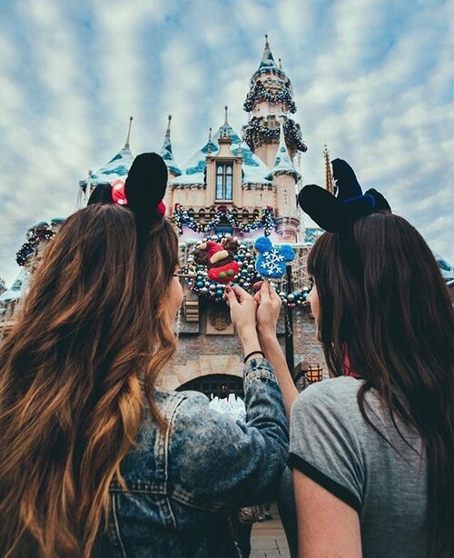 Chicas de cabello largo oscuro rizado con orejas de Mickey Mouse mirando el castillo de Disney