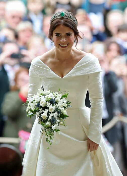 Eugenia de York  el día de su boda luciendo un vestido blanco de encaje con un ramo de novia con flores blancas 