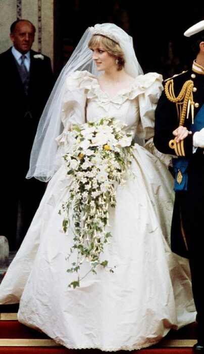 Diana Spencer  el día de su boda luciendo un vestido blanco de encaje con un ramo de novia con flores blancas 