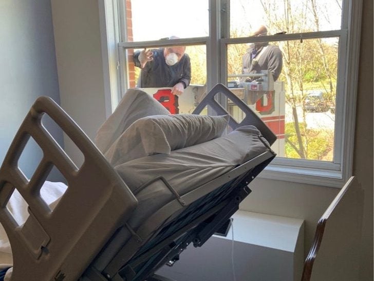 Hombre despidiéndose de su madre desde la ventana en el hospital