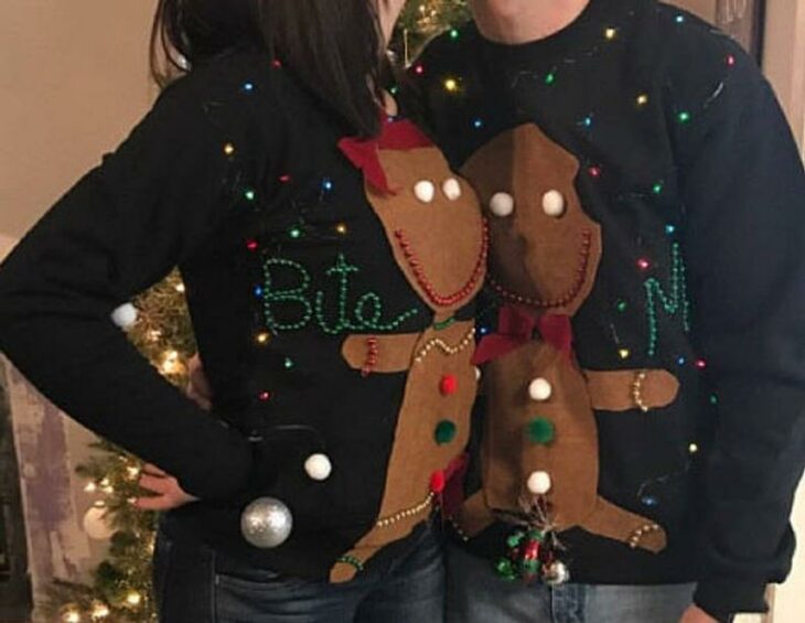 Pareja con suéter navideño decorado con galletas de jengibre 