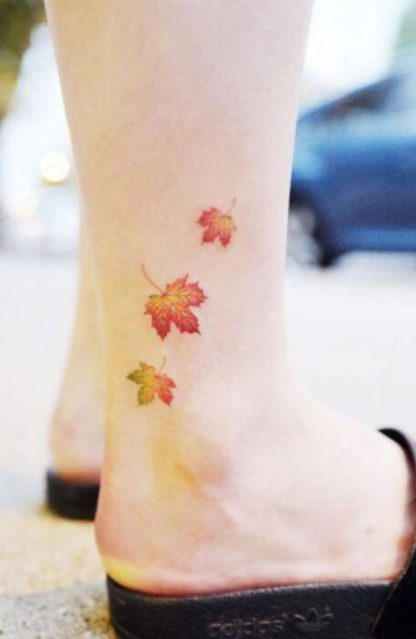 Tatuaje pequeño sobre el tobillo de tres hojitas de maple en otoño