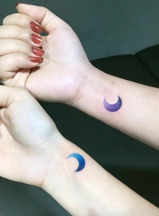 Tatuaje complementario de dos lunas en diferentes colores sobre la muñeca