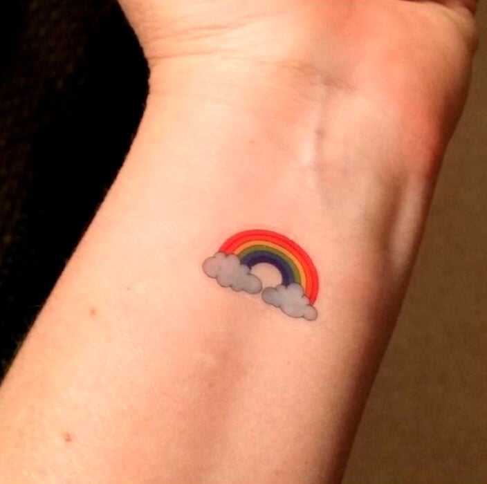 Tatuaje pequeño sobre la muñeca de un arcoíris