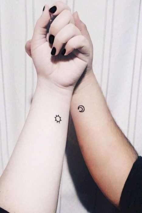 Tatuaje complementario de un sol y una luna pequeños en la zona de la muñeca