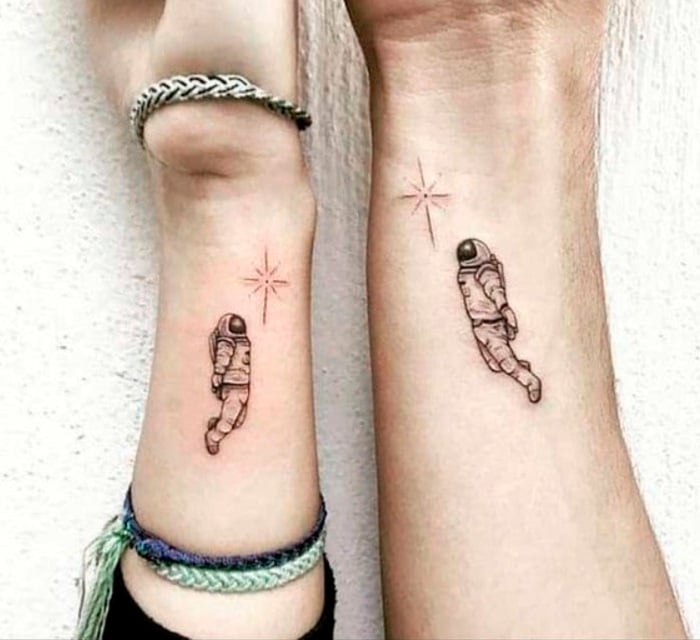Tatuaje complementario de astronautas que alcanzan una estrella sobre la sobra de la muñeca