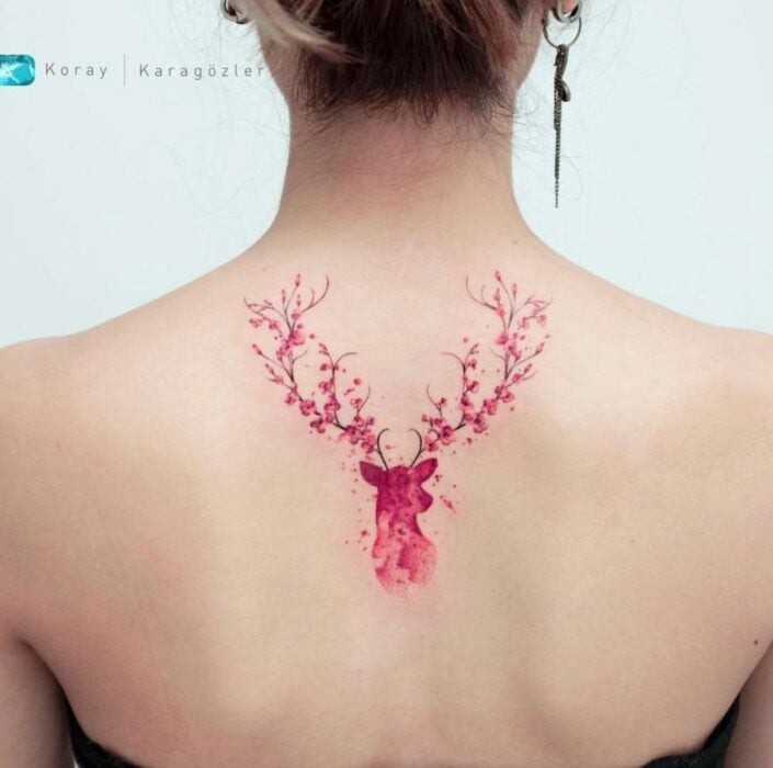 Chica con un tatuaje de color rosa en forma de de venado con flores en sus cuernos