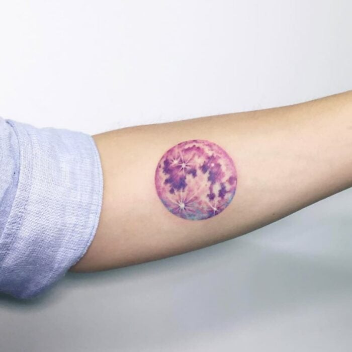Chica con un tatuaje de color rosa en forma de un circulo con flores 