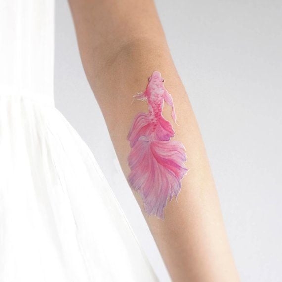 Chica con un tatuaje de color rosa en forma de pez  